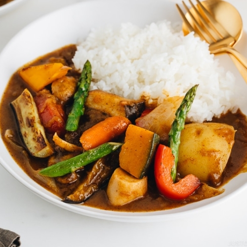 A white plate containing Vegetarian Japanese Curry along with steamed rice.