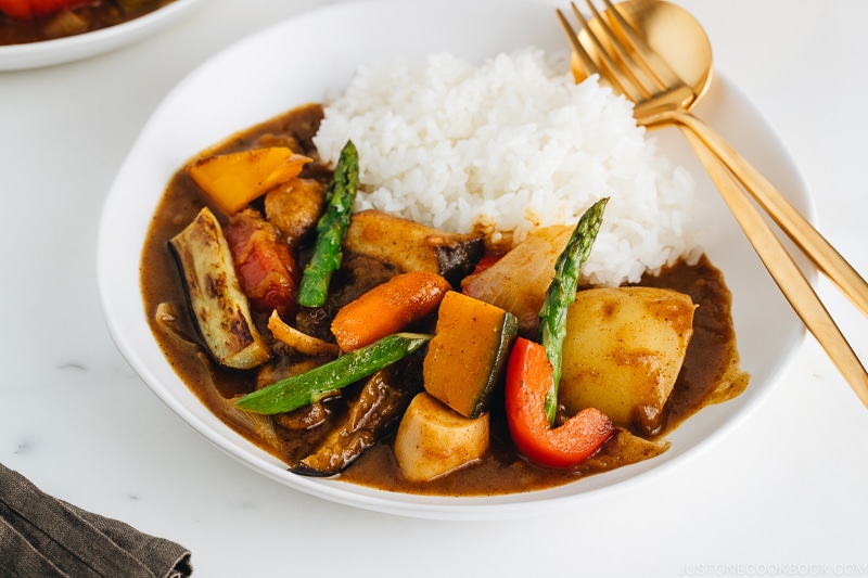 A white plate containing Vegetarian Japanese Curry along with steamed rice.