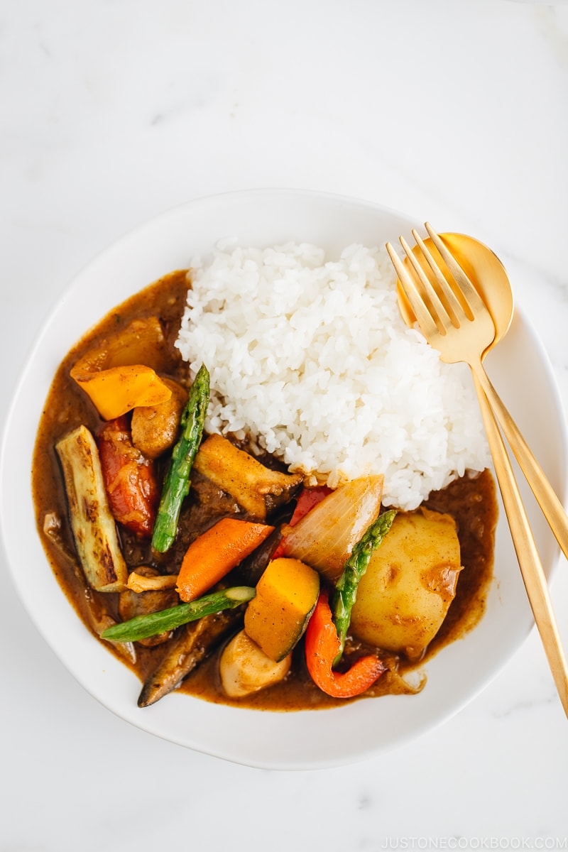 A white plate containing Vegetarian Japanese Curry along with steamed rice.