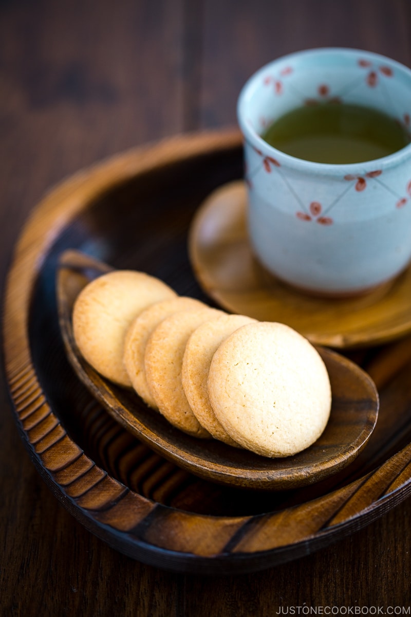 A wooden plate containing round butter cookies.