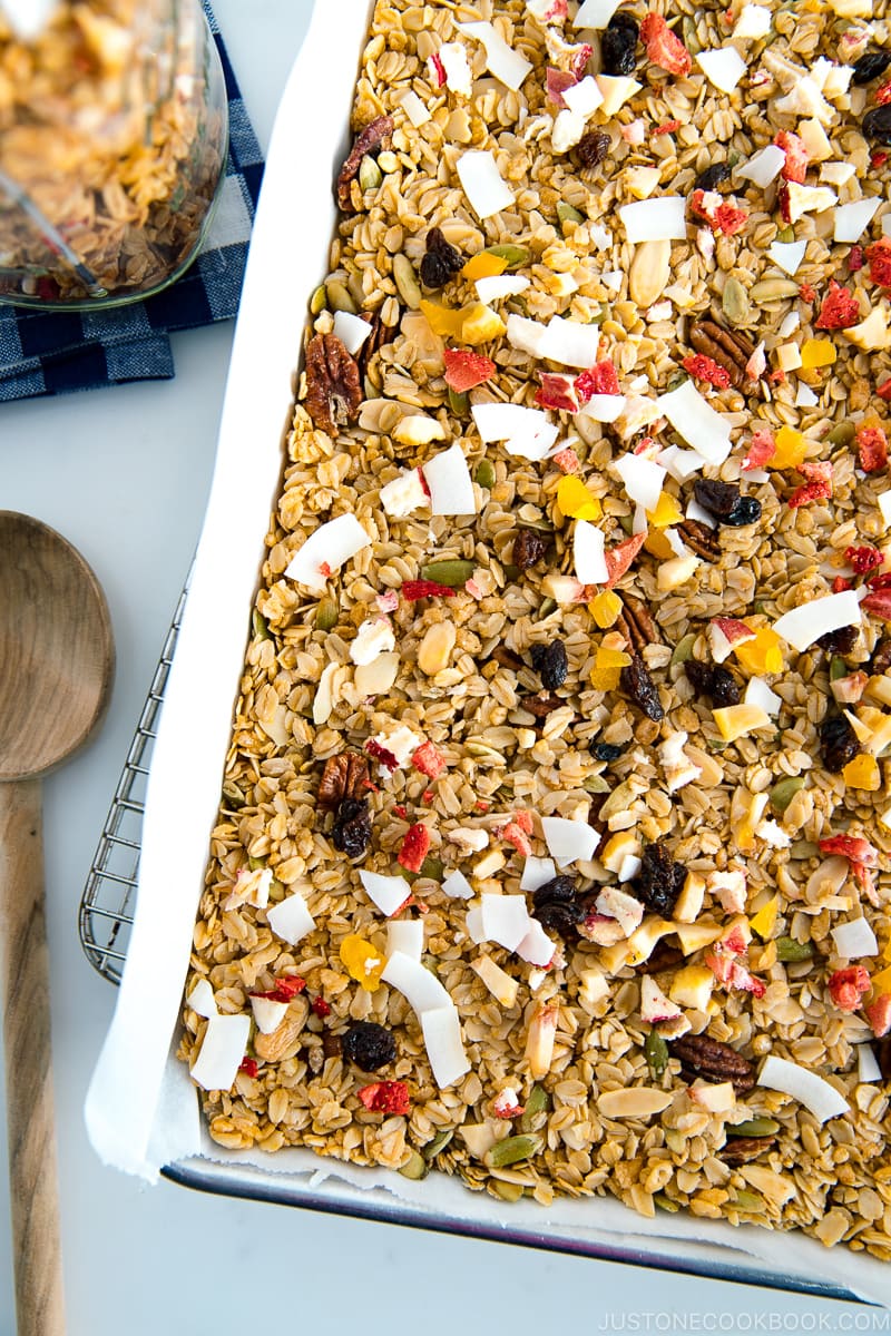 A baking sheet containing homemade granola, being just taken out of the oven.