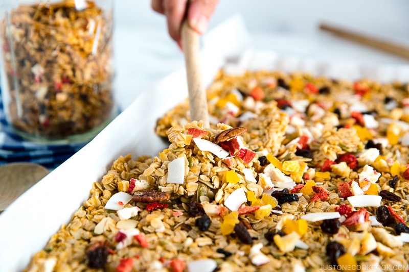 A baking sheet containing homemade granola, being just taken out of the oven.