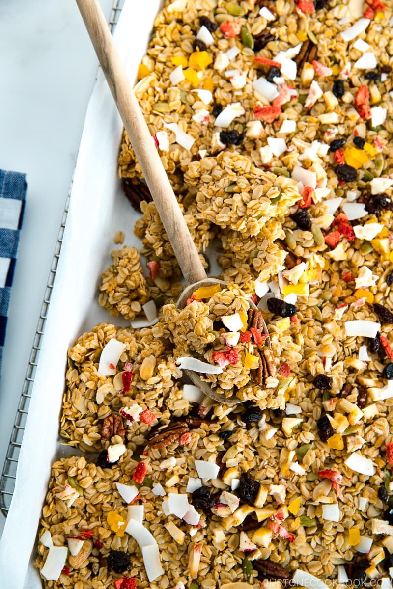 A baking sheet containing homemade granola, being just taken out of the oven.