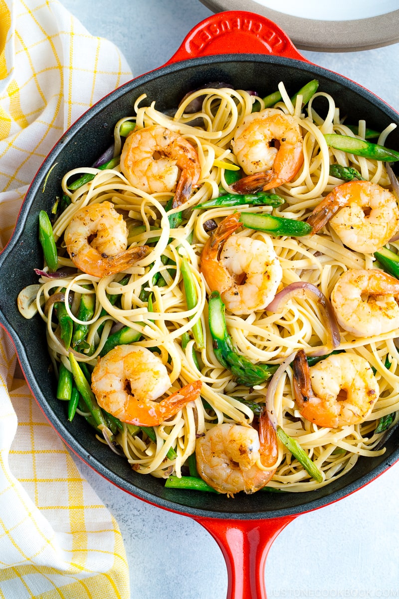 A red skillet containing Japanese-style Pasta with Shrimp and Asparagus.