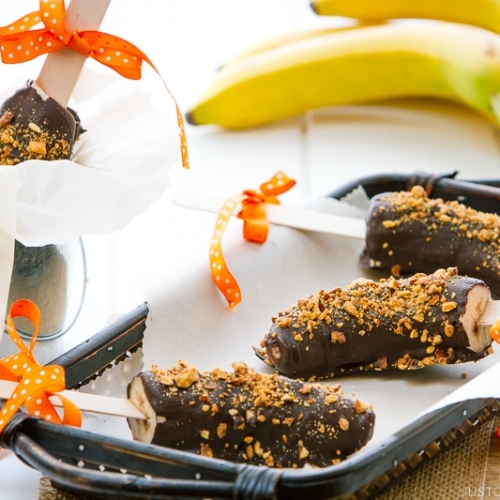 Frozen chocolate bananas sprinkled with almonds.