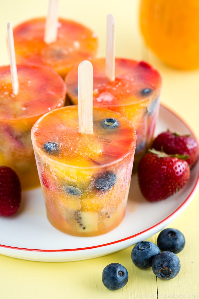 Homemade fruit popsicles on a white plate.