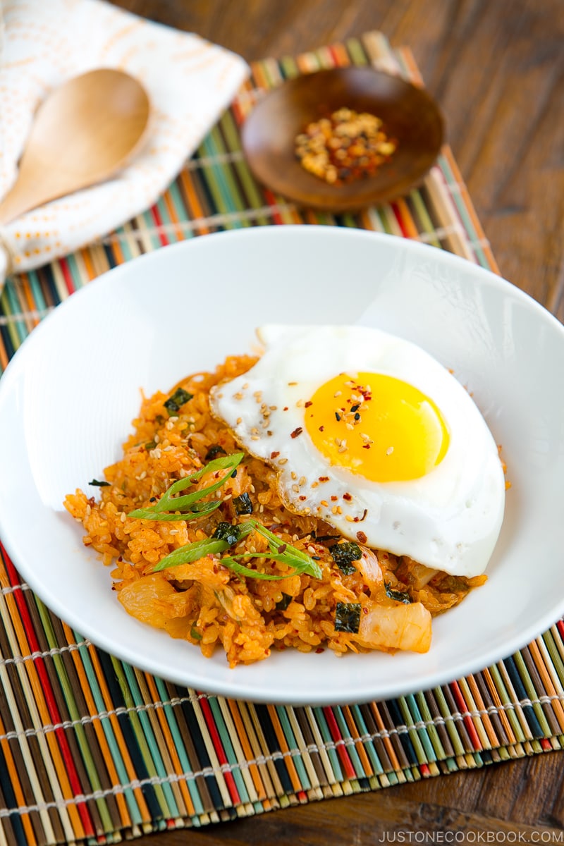 A white plate containing kimchi fried rice with a fried egg on top.