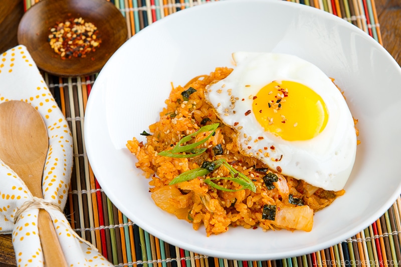 A white plate containing kimchi fried rice with a fried egg on top.