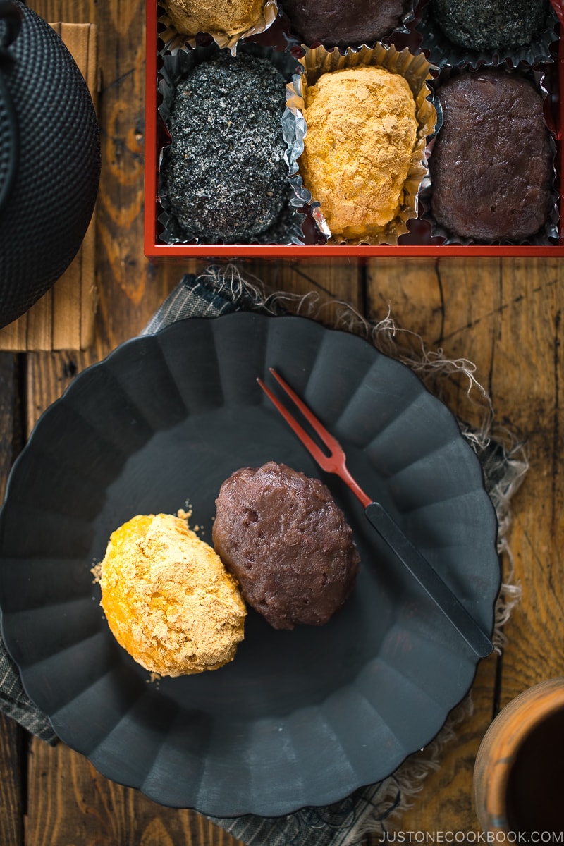 A lacquer box containing Ohagi (Botamochi) and some of them are served on a black plate.