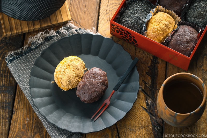 A lacquer box containing Ohagi (Botamochi) and some of them are served on a black plate.