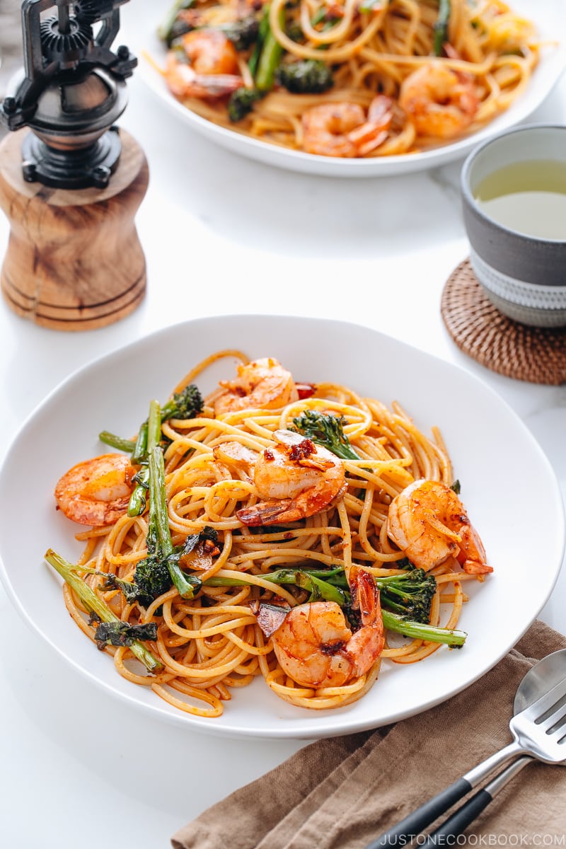 A white plate containing Japanese Pasta with Shrimp and Broccolini.