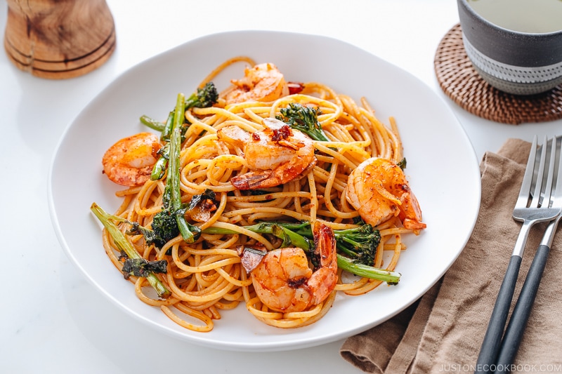 A white plate containing Japanese Pasta with Shrimp and Broccolini.