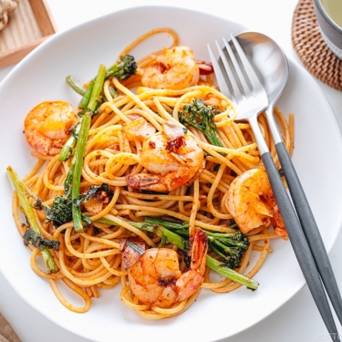 A white plate containing Japanese Pasta with Shrimp and Broccolini.