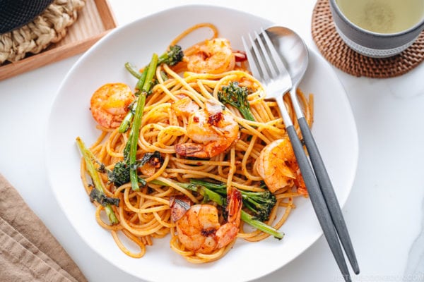 A white plate containing Japanese Pasta with Shrimp and Broccolini.