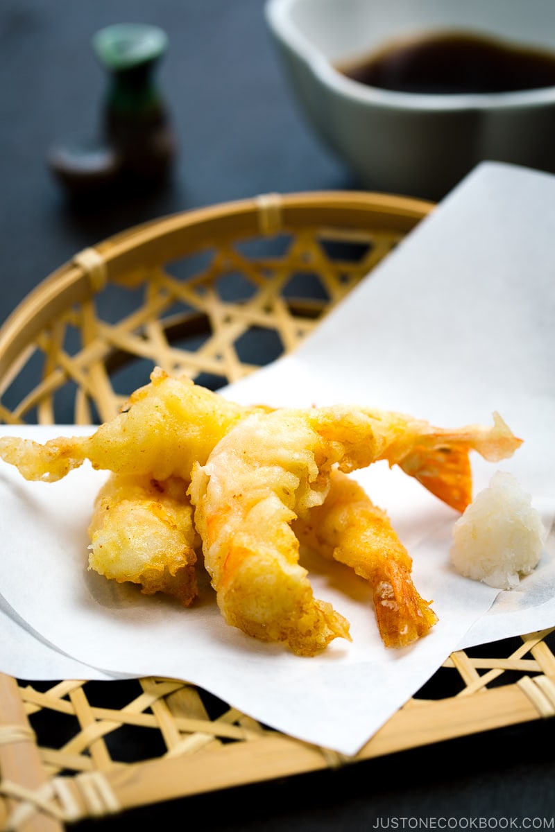 Shrimp tempura on a plate along with the dipping sauce.