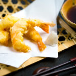 Shrimp tempura on a plate along with the dipping sauce.