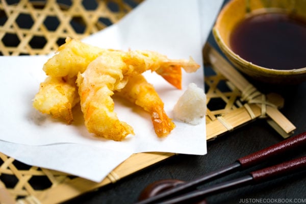 Shrimp tempura on a plate along with the dipping sauce.