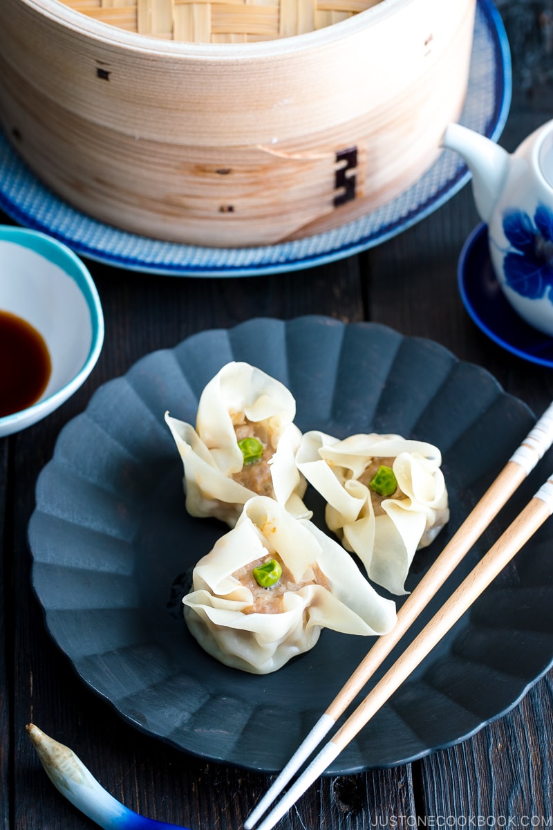 A black plate containing pork shumai (steamed pork dumplings).