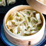 A bamboo steamed basket containing pork shumai (steamed pork dumplings).