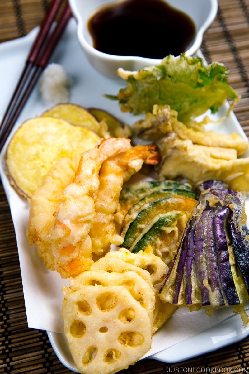 Shrimp and vegetable tempura on a plate along with the dipping sauce.