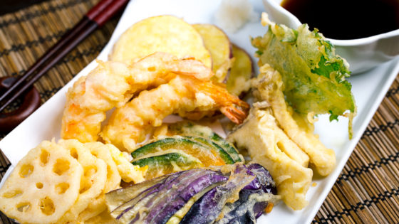 Shrimp and vegetable tempura on a plate along with the dipping sauce.