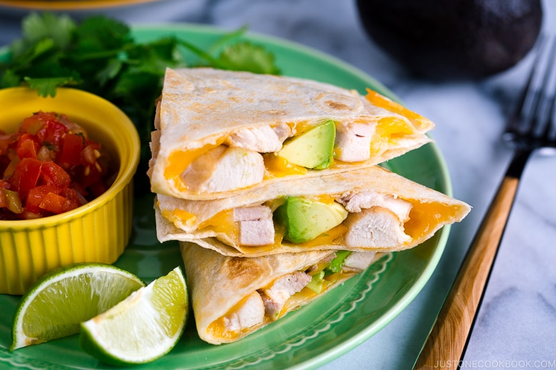 A green plate containing teriyaki chicken quesadilla.