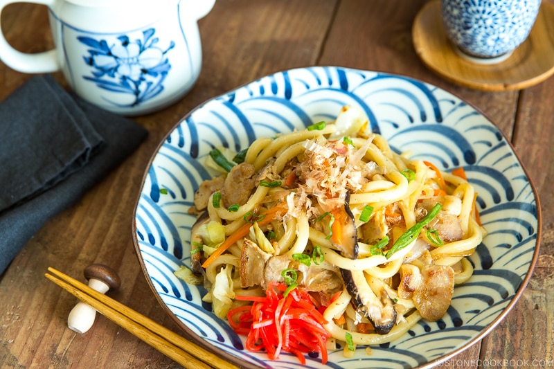 A Japanese blue and white plate containing stir fried udon noodles called Yaki Soba.