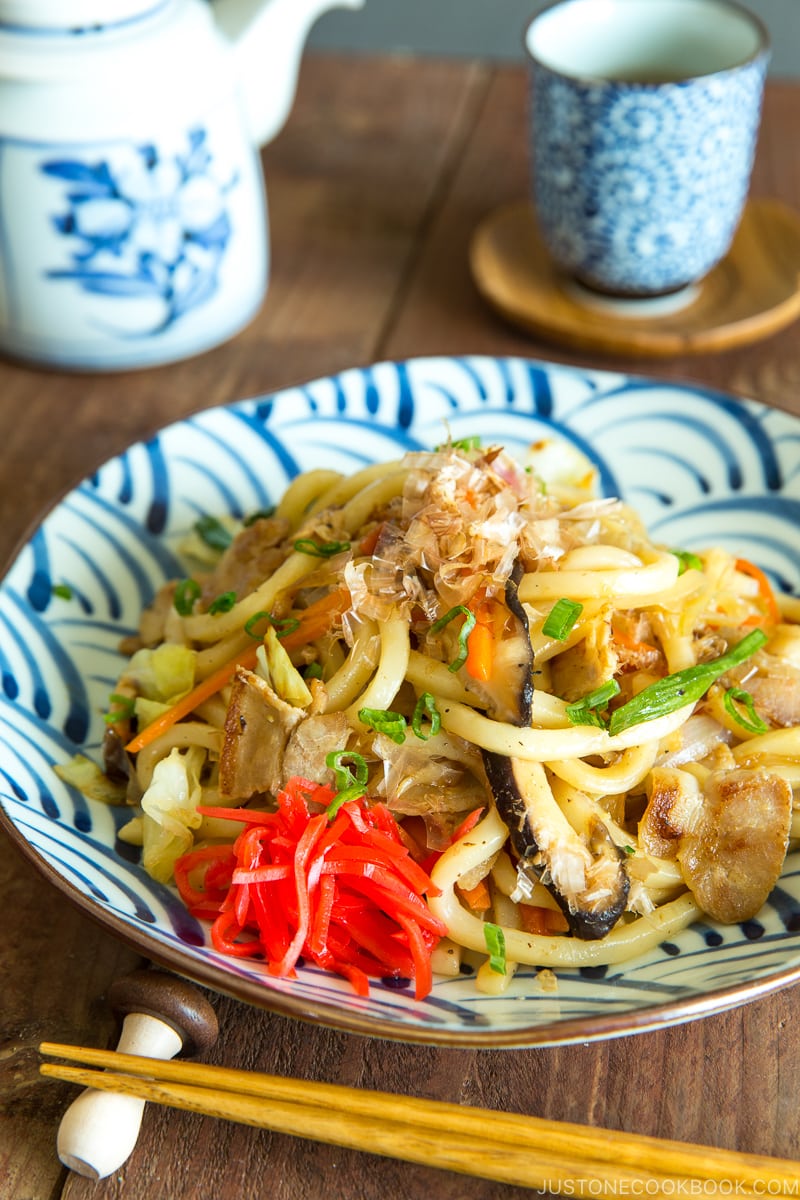 A Japanese blue and white plate containing stir fried udon noodles called Yaki Soba.