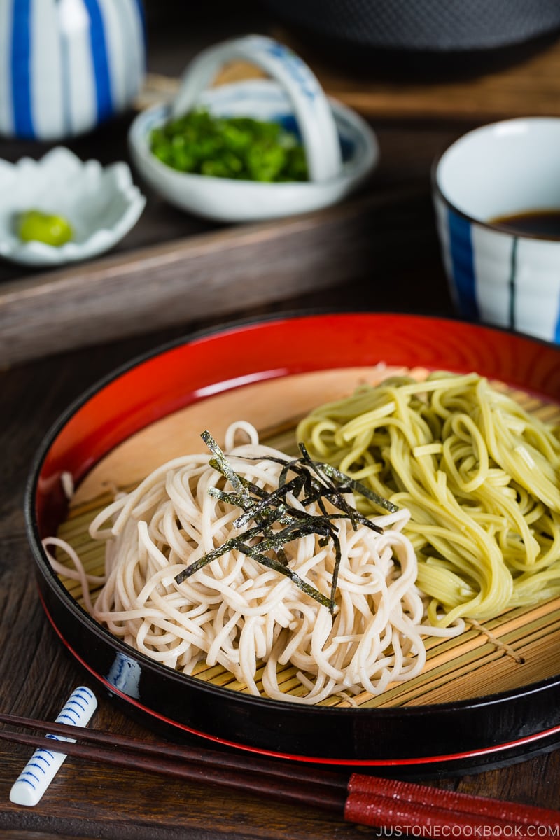 Two kinds of soba noodles served on a Japanese bamboo, garnished with shredded nori sheet.