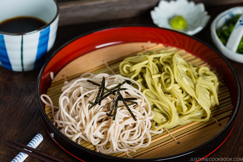 Two kinds of soba noodles served on a Japanese bamboo, garnished with shredded nori sheet.