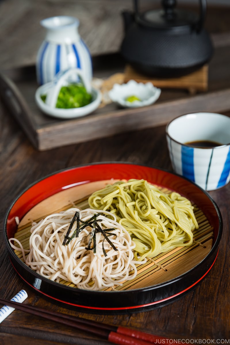 Two kinds of soba noodles served on a Japanese bamboo, garnished with shredded nori sheet.