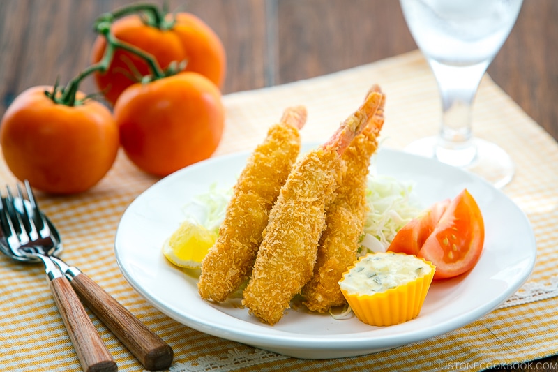 A white plate containing Ebi Fry served with tartar sauce.