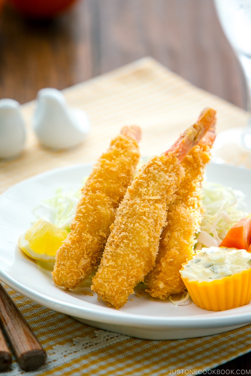 A white plate containing Ebi Fry served with tartar sauce.