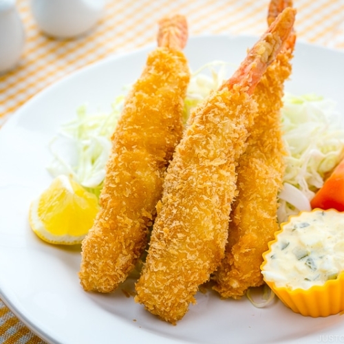 A white plate containing Ebi Fry served with tartar sauce.