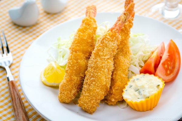 A white plate containing Ebi Fry served with tartar sauce.