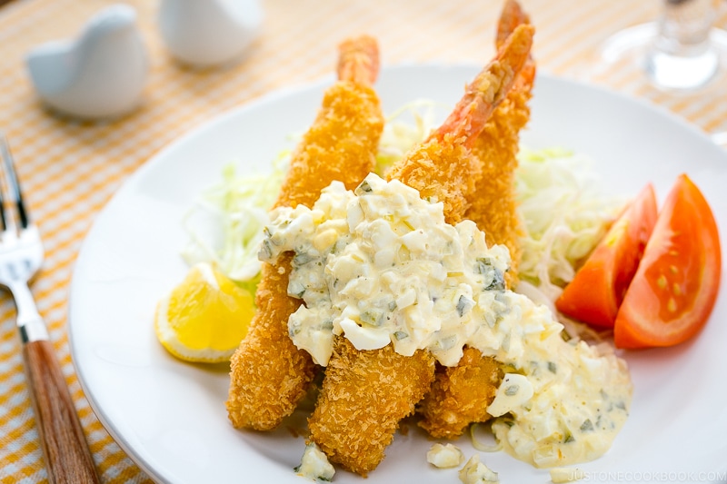A white plate containing Ebi Fry served with tartar sauce.