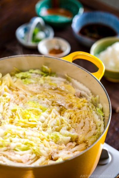 A Dutch oven containing thousand layers of cabbage leaves and pork belly slices simmered in a savory dashi broth.