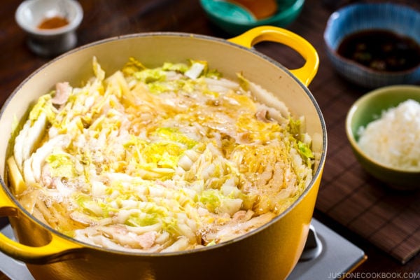 A Dutch oven containing thousand layers of cabbage leaves and pork belly slices simmered in a savory dashi broth.