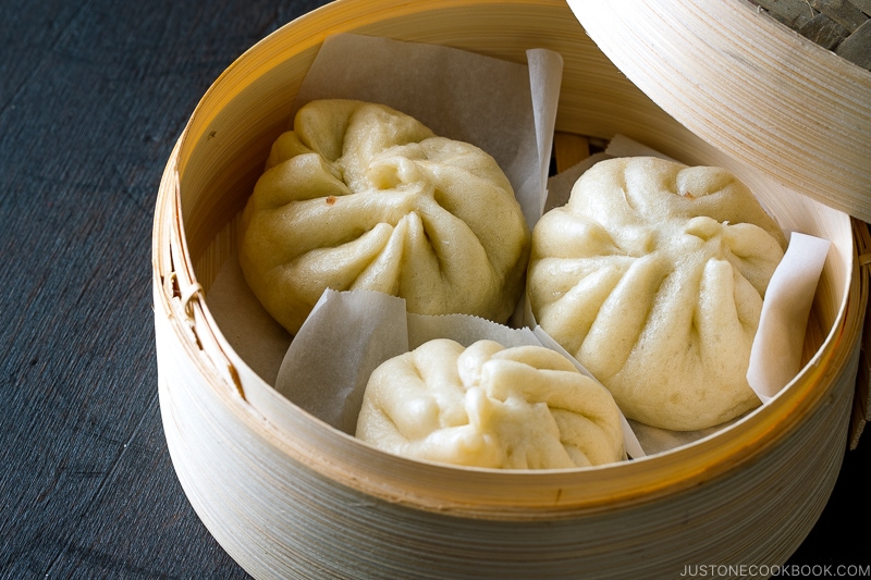 A mini bamboo steamer containing Steamed Pork Buns (Nikuman).