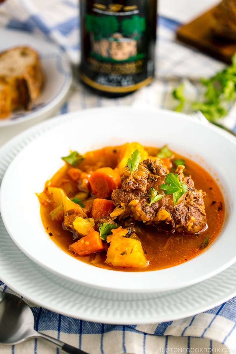 White bowl containing flavorful oxtail soup served with rustic bread.