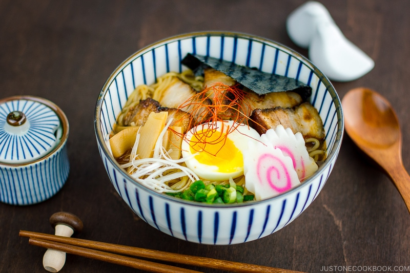 A bowl containing Spicy Shoyu Ramen topped with soft boiled egg, fish cake, nori, and fall-apart tender chashu.