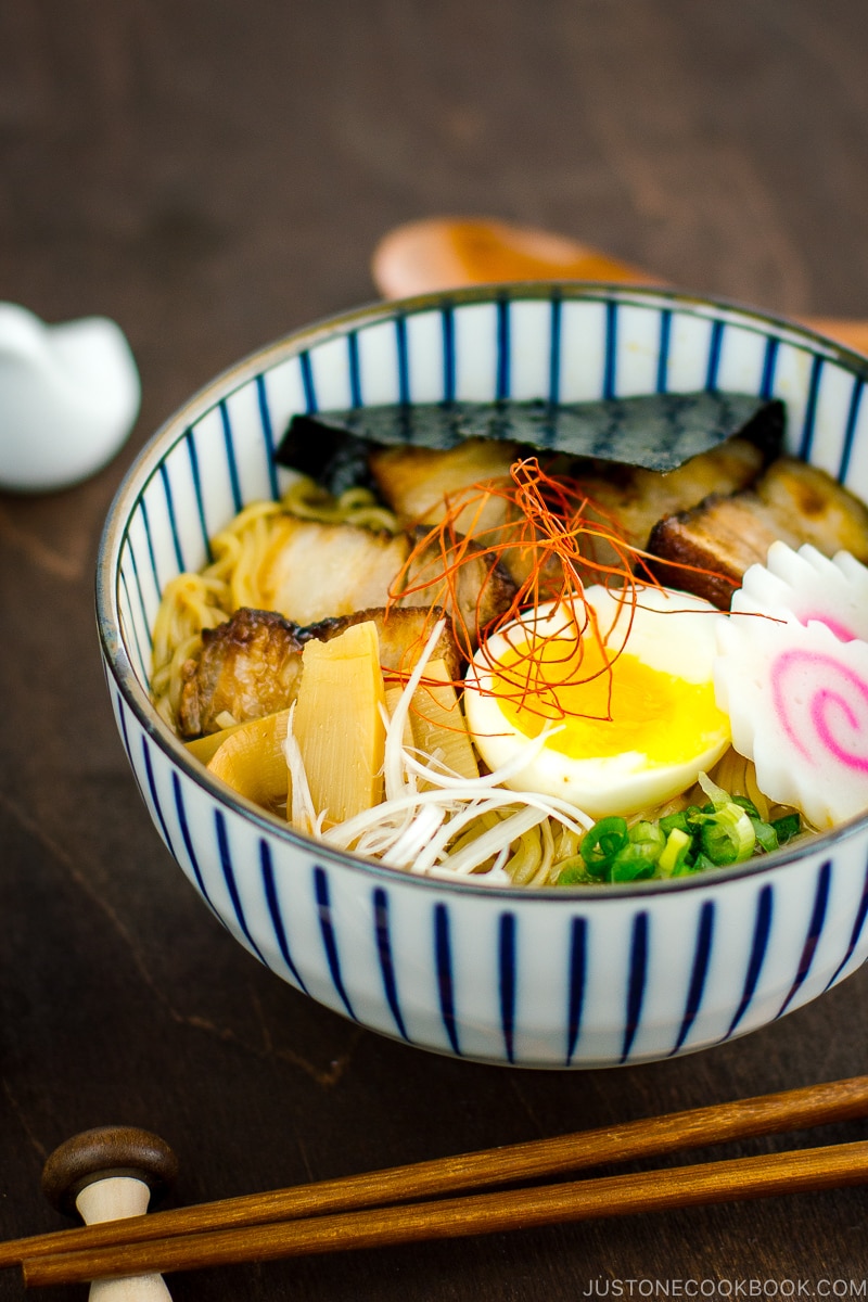 A bowl containing Spicy Shoyu Ramen topped with soft boiled egg, fish cake, nori, and fall-apart tender chashu.