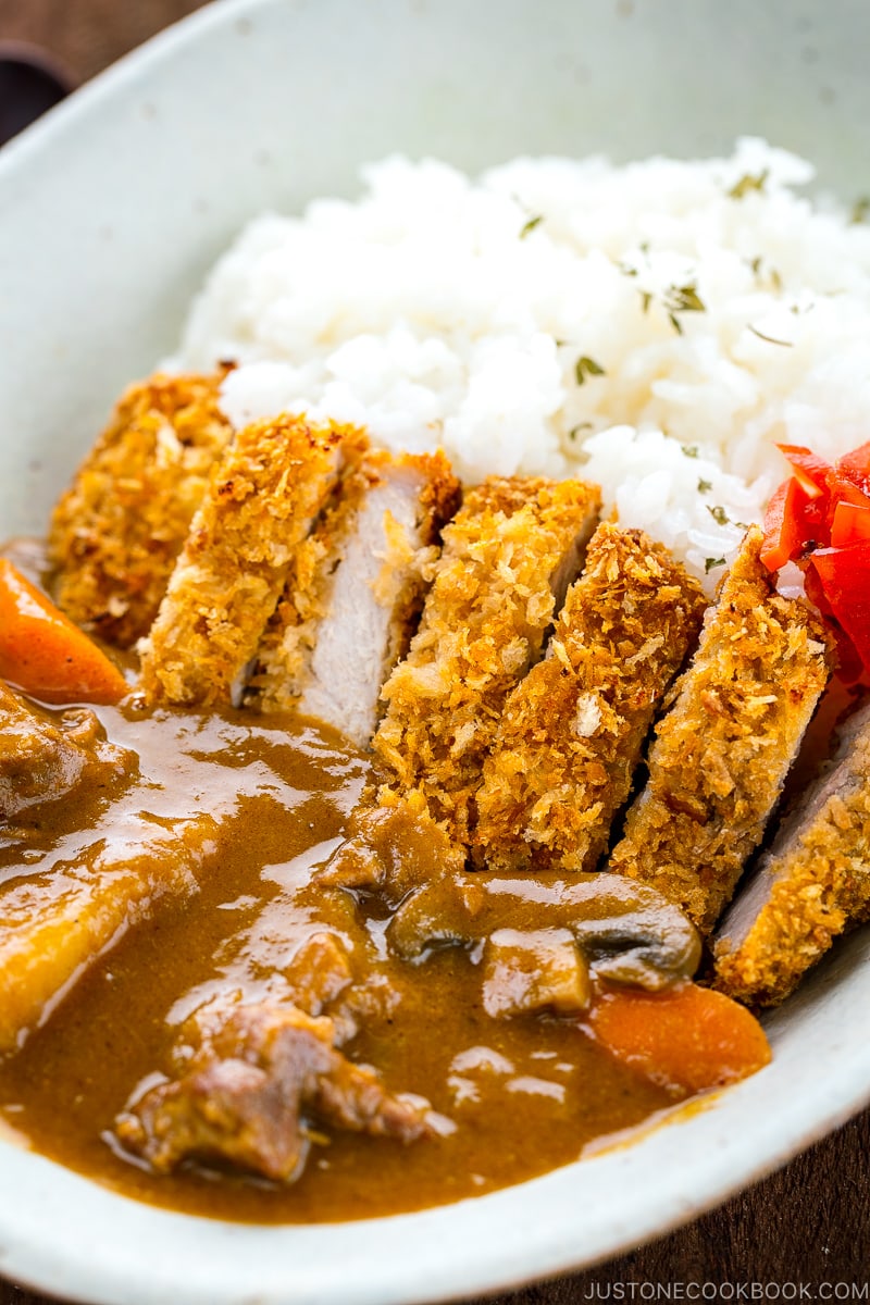 A white oval bowl containing Katsu Curry garnished with Fukujinzuke.