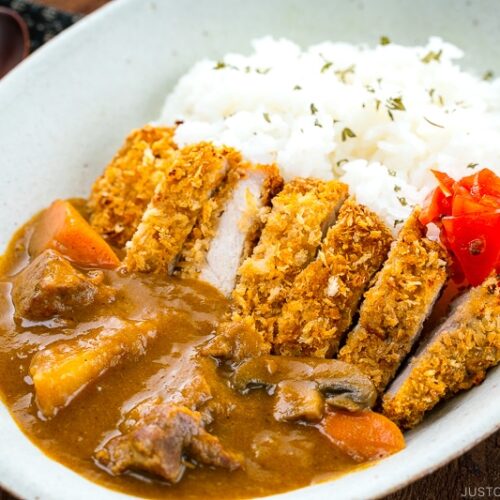 A white oval bowl containing Katsu Curry garnished with Fukujinzuke.