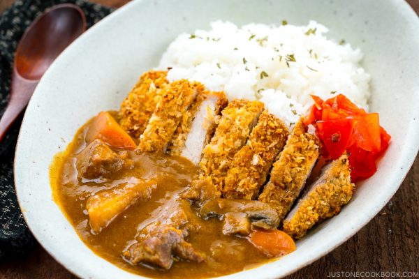 A white oval bowl containing Katsu Curry garnished with Fukujinzuke.