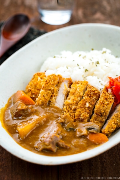 A white oval bowl containing Katsu Curry garnished with Fukujinzuke.