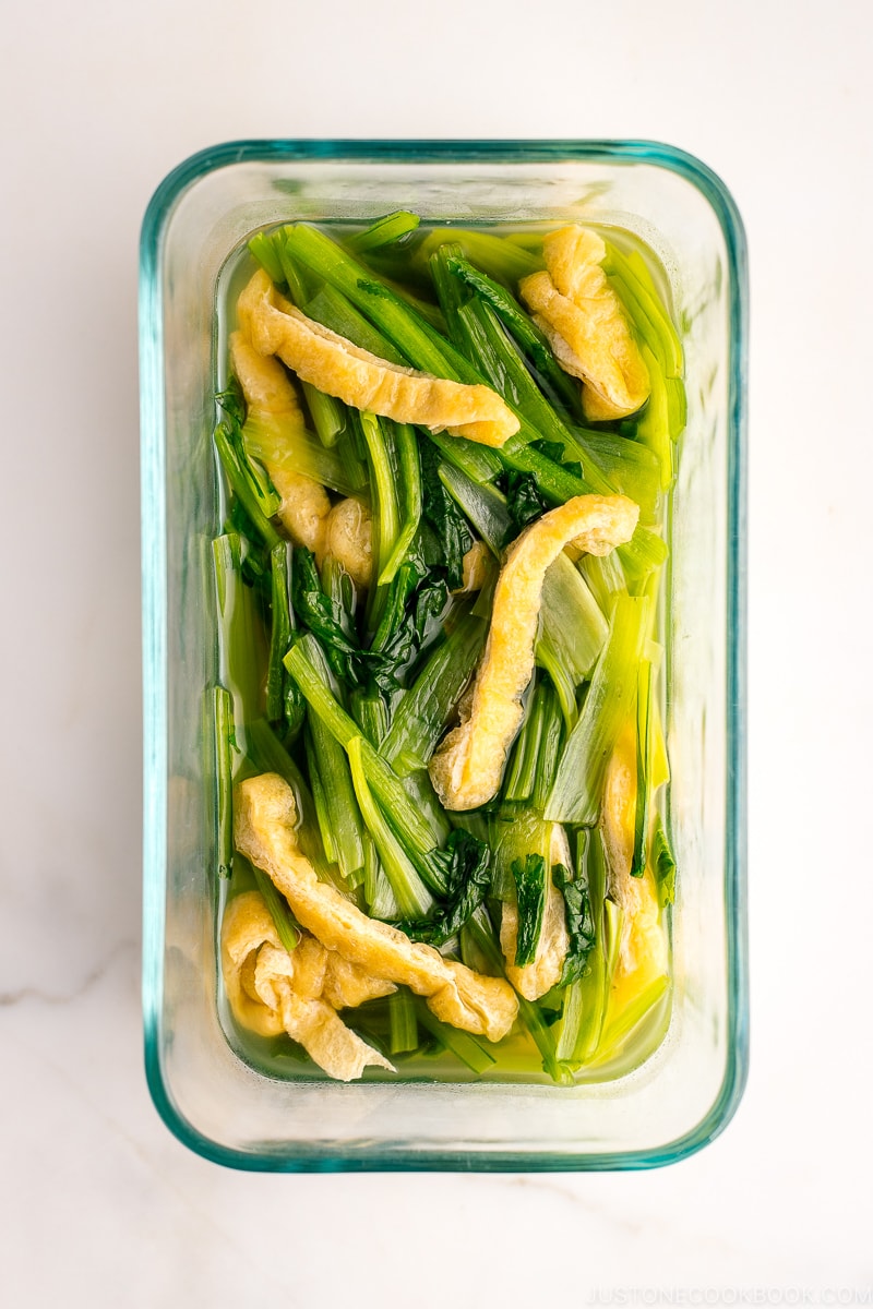 A pyrex container containing Simmered Fried Tofu and Greens.