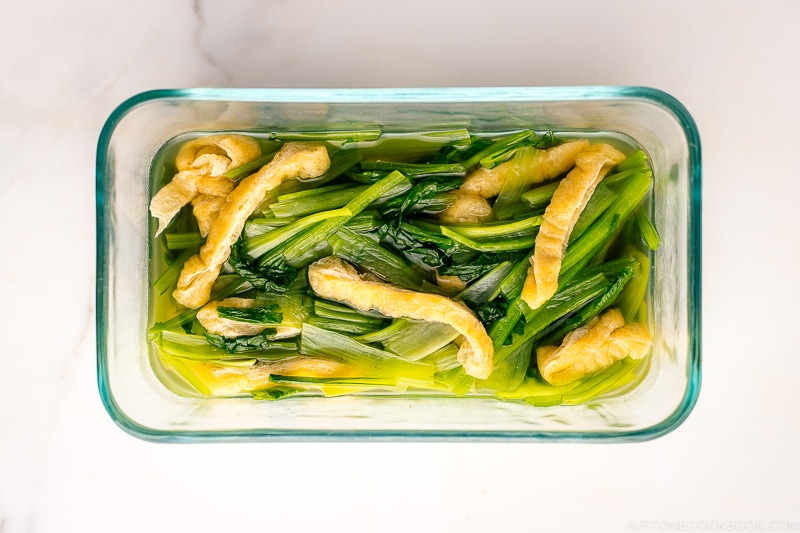 A pyrex container containing Simmered Fried Tofu and Greens.