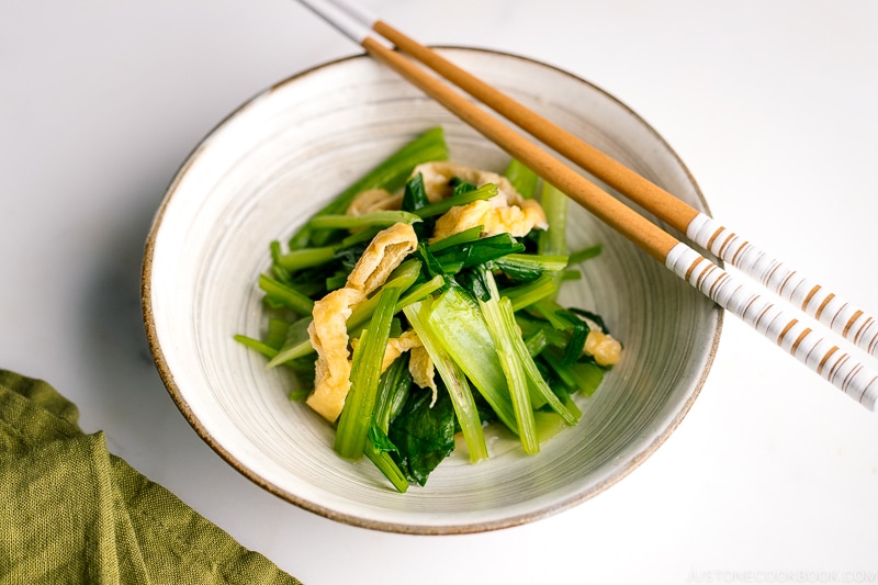 A white Japanese ceramic bowl containing Simmered Fried Tofu and Greens.