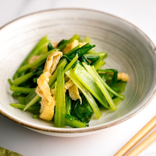 A white Japanese ceramic bowl containing Simmered Fried Tofu and Greens.